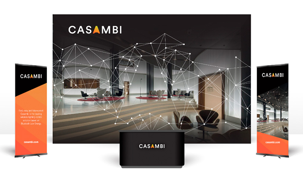 Design materials on computer screen and brochures in black, orange, white and gray tones.