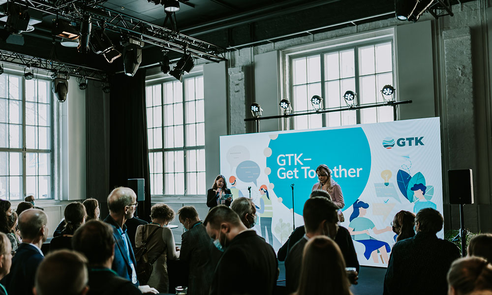 An event organized for GTK with dim lighting where the audience listens to a person give a speech.