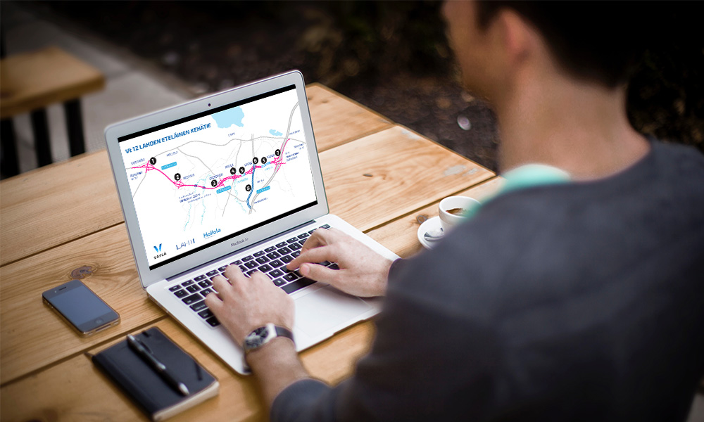 A person, whose back is facing the camera, is sitting in front of a laptop that features an image of a map.